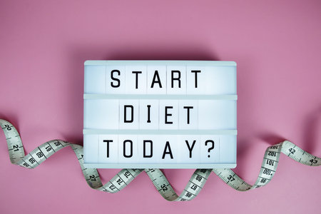 Start diet today? letterboard text on LED Lightbox and Measuring tape on pink background, Healthcare conceptの写真素材