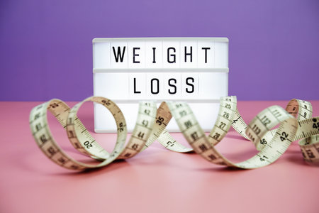 Weight Loss letterboard text on LED Lightbox and Measuring tape on pink and purple background, Healthcare conceptの写真素材