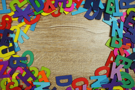 Random colorful letterpress alphabet with space copy top view on wooden backgroundの写真素材