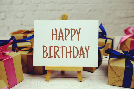 Happy Birthday text on paper card with gift box present on wooden backgroundの写真素材