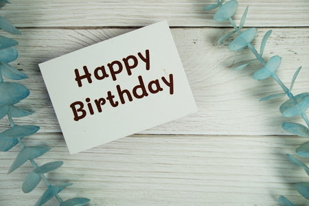 Happy Birthday text on paper card with top view on wooden backgroundの写真素材