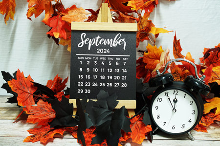 September 2024 monthly calendar with maple leaf decoration on wooden background for planning and...