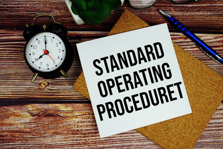 Standard Operating Procedure text written on paper card with alarm clock top viewの写真素材