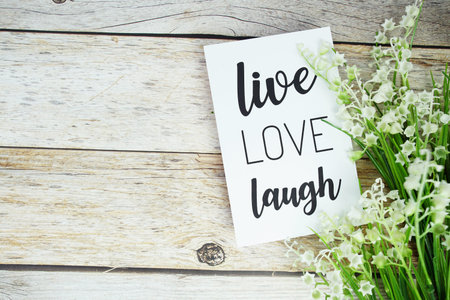Live Love Laugh text on paper card with flowers bouquet top view on wooden background