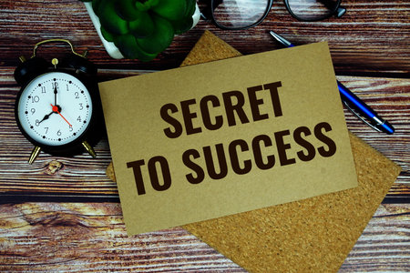 Secret to Success text written on paper torn with alarm clock top view on wooden backgroundの写真素材