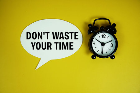 Don't waste your time text on speech bluble with alarm clock top view on yellow background
