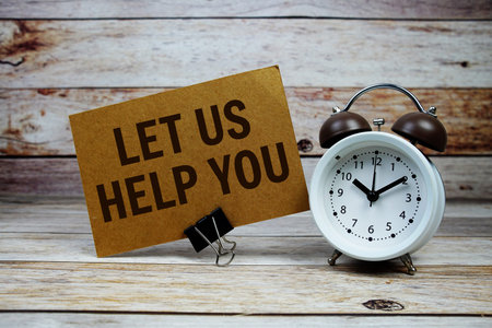 Let us help you text on paper card with alarm clock on wooden background