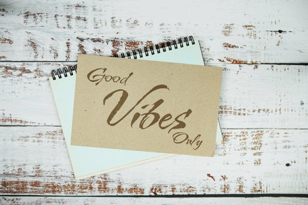 Good Vibes only text message on paper card with flowers border frame on wooden backgroundの写真素材