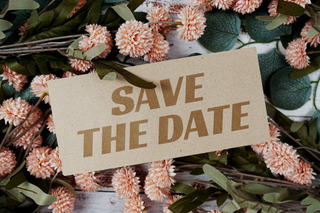 Save the Date text message on paper card with flowers border frame on wooden background