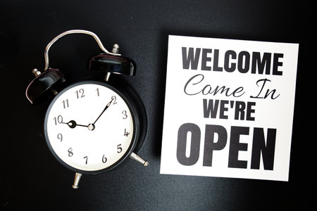 Welcome We're Open text with alarm clock on black backgroundの写真素材