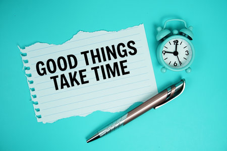 Good Things Take Time quotes text on paper torn with alarm clock top view on blue backgroundの写真素材