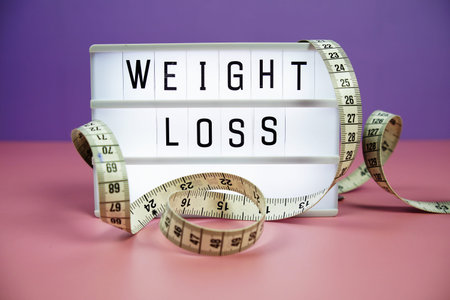 Weight Loss letterboard text on LED Lightbox and Measuring tape on pink and purple background,...
