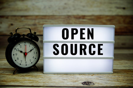 Open Source text on LED lightbox with alarm clock on wooden backgroundの写真素材