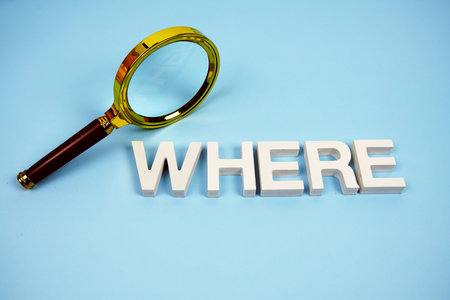 WHERE word with magnifying glass top view on blue background