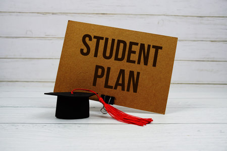 Student Plan text on paper card with small graduation cap on wooden background