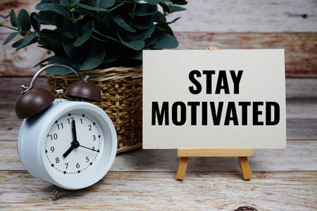 Stay Motivated text motivational and inspiration quote with alarm clock on wooden backgroundの写真素材