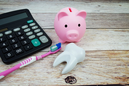 Toothbrush dental hygiene concept with calculator and piggy saving on wooden background, Dental money and dentist treatment costsの写真素材