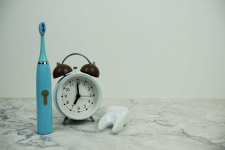 Toothbrush with alarm clock and white tooth model dental hygiene concept on marble background