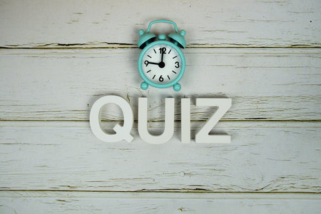 Quiz alphabet letters with alarm clock top view on wooden