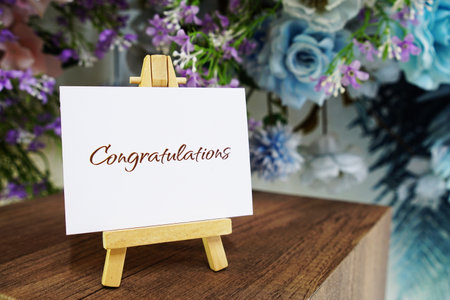 Congratulations text write on paper card with wooden easel and flowers decoration on wooden backgroundの写真素材