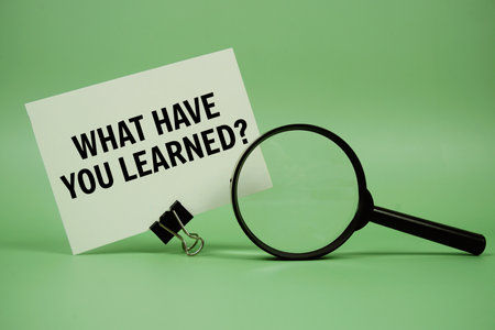 What have you Learned? text message on paper card with magnifying glass on green backgroundの写真素材