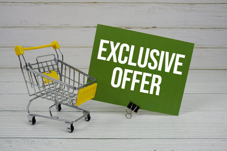Exclusive Offer text message on paper card with mini trolley shopping cart on wooden background