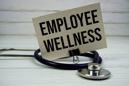 Employee Wellness Program text message on paper card with stethoscope on wooden backgroundの写真素材