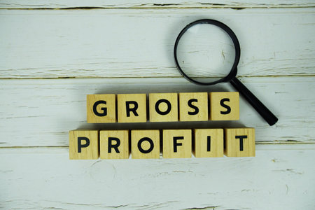 Gross Profit with wooden blocks alphabet letters and magnifying glass on wooden backgroundの写真素材