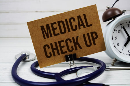 Medical Check Up text message on paper card with stethoscope and alarm clock on wooden backgroundの写真素材