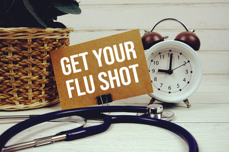 Get Your Flu Shot text message on paper card with stethoscope on wooden backgroundの写真素材