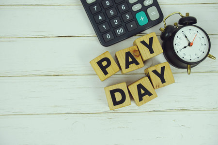 Pay Day alphabet letters with calculator and alarm clock top view on wooden background