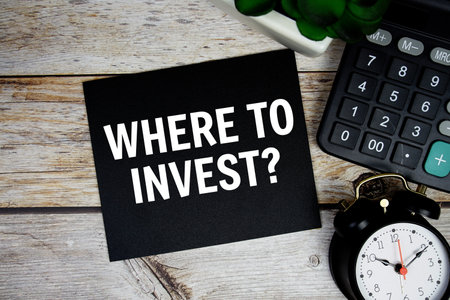 Where to invest? text with alarm clock and calculator on wooden background, Business conceptの写真素材