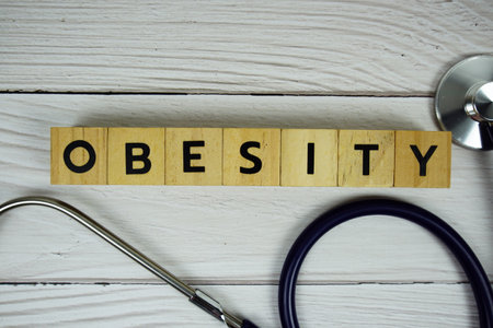 Obesity with wooden blocks alphabet letters and stethoscope on wooden background, Healthy and wellness conceptの写真素材