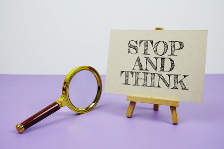 Stop and Think text on paper card with magnifying glass on purple backgroundの写真素材