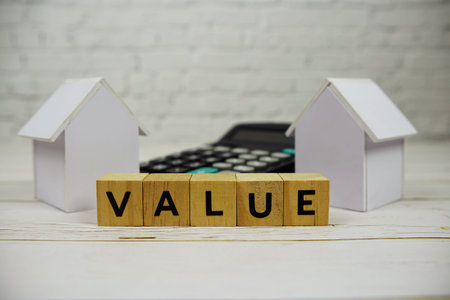 Value with wooden blocks alphabet letters and calculator, white house model on wooden background