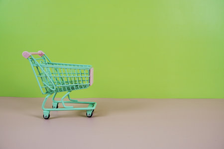 Mini Trolley shopping cart with space for text on pink and green backgroundの写真素材