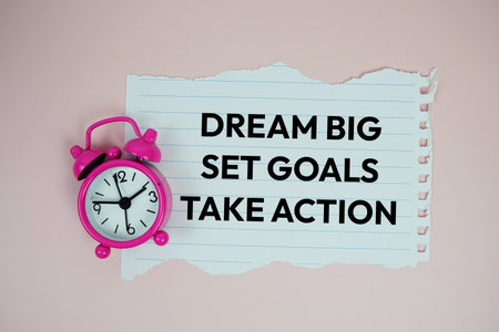 Dream Big, Set Goals, Take Action text motivational and inspiration quote with alarm clock on pink backgroundの写真素材
