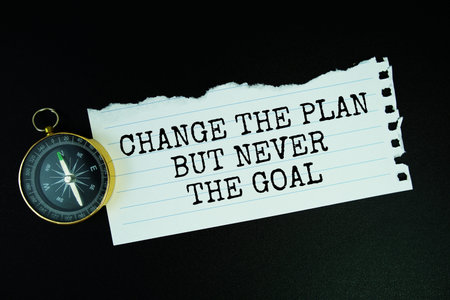 Change The Plan But Never The Goal text motivational and inspiration quote with compass on black...