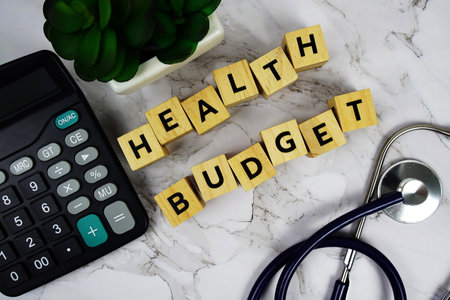 Health Budget with wooden blocks alphabet letters and stethoscope and calculator on marble backgroundの写真素材