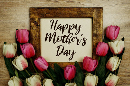 Happy Mother's Day text with tulip flowers bouquet on wooden background
