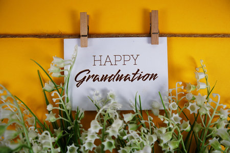 Happy Graduation text on paper card with flower blooming decoration on yellow backgroundの写真素材