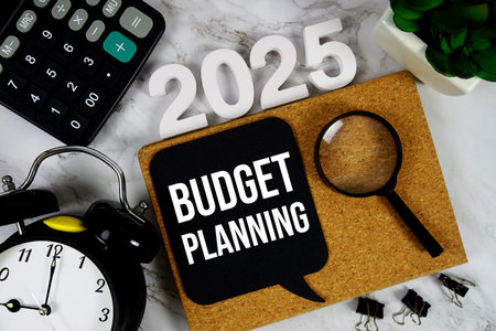 Budget Planning 2025 text message with calculator, alarm clock and magnifying glass on wooden...