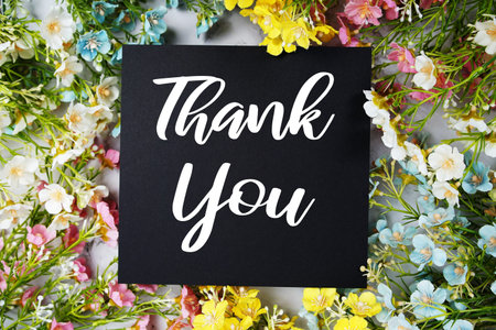 Thank You text with flowers frame decoration top view on blue backgroundの写真素材