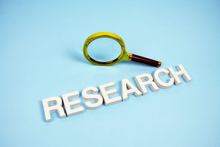 Research word with magnifying glass top view on blue background