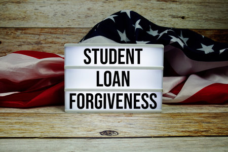 Student Loan Forgiveness text messege with USA flag on wooden backgroundの写真素材