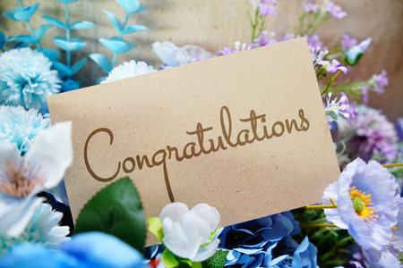 Congratulations text write on paper card with flowers decoration on wooden backgroundの写真素材
