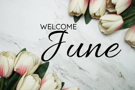 Welcome June text with alarm clock and tulip flower bouquet on marble backgroundの写真素材