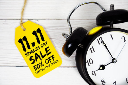 11.11 Singles Day Sale 50% off Promotion on price tag with alarm clock on wooden backgroundの写真素材