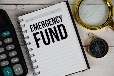 Emergency Fund text on notepad with calculator and magnifying glass on wooden backgroundの写真素材