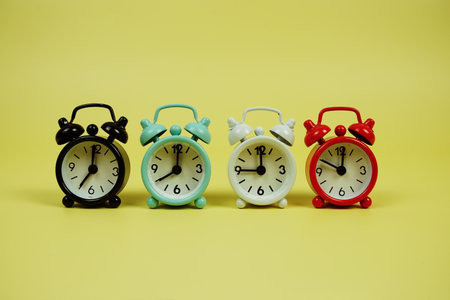 Alarm clocks with different time on yellow backgroundの写真素材